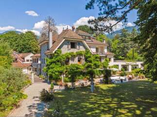 Discover the charm of this stunning property, showcasing a beautiful stone facade and a lush, green landscape.
