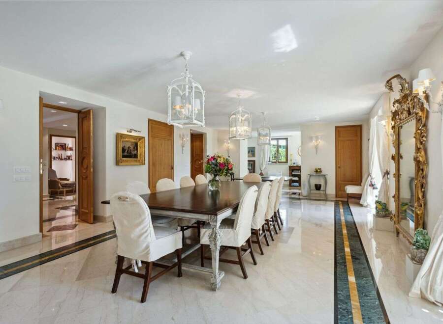 Step into luxury with this exquisite dining room, featuring a grand wooden table and elegant white chairs.