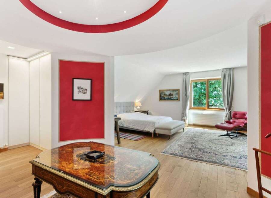Step into luxury with this stunning bedroom featuring a unique red accent wall and elegant design.