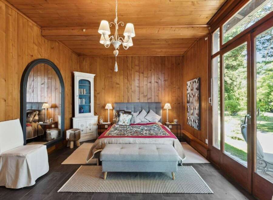 Step into this inviting bedroom, featuring warm wood paneling and a cozy ambiance.