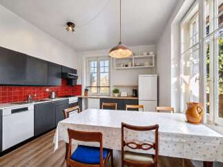 This charming kitchen features sleek black cabinetry contrasted with a vibrant red tiled backsplash, offering a modern and stylish aesthetic.