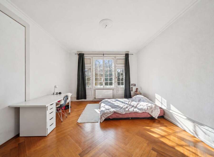 Discover this charming bedroom featuring a spacious white desk with ample storage, perfect for a home office setup.
