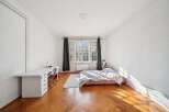 Discover this charming bedroom featuring a spacious white desk with ample storage, perfect for a home office setup.