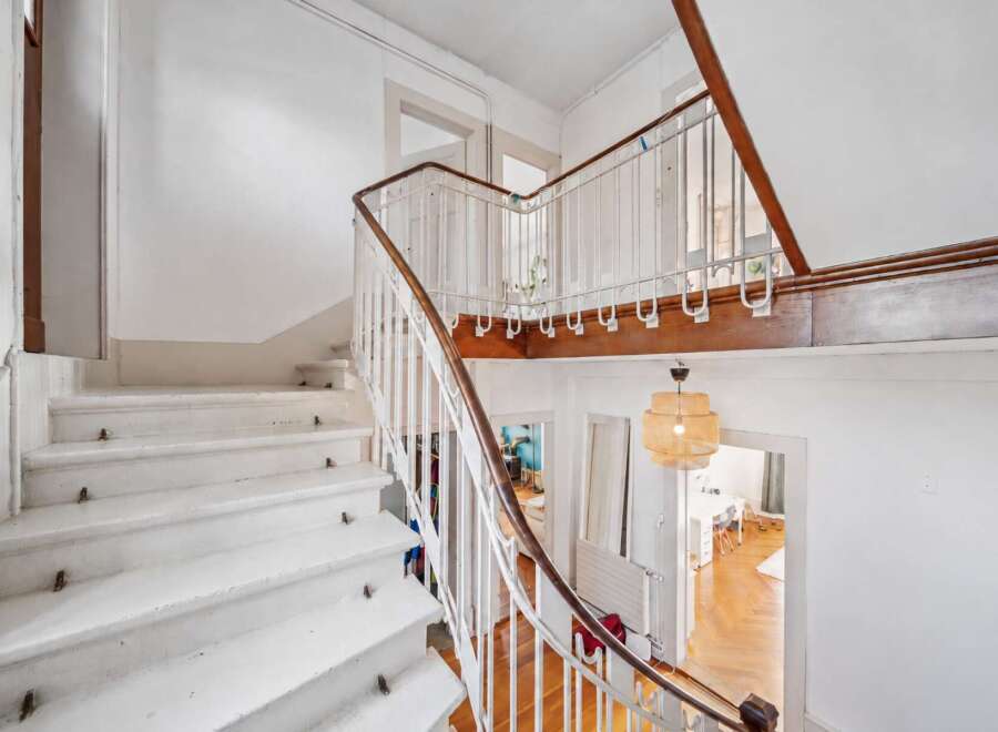 Ascend to new heights in this charming staircase, featuring a classic white railing with a warm wooden handrail.