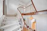 Ascend to new heights in this charming staircase, featuring a classic white railing with a warm wooden handrail.