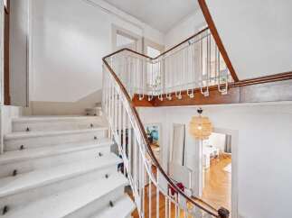 Ascend to new heights in this charming staircase, featuring a classic white railing with a warm wooden handrail.