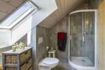 This charming bathroom features a modern design with a unique sloped ceiling and a skylight that floods the space with natural light.