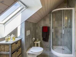 This charming bathroom features a modern design with a unique sloped ceiling and a skylight that floods the space with natural light.
