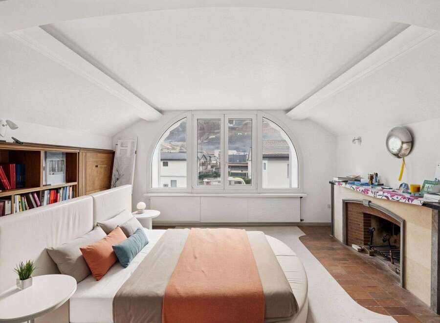 This stunning bedroom boasts a unique architectural design with an arched window offering breathtaking views.