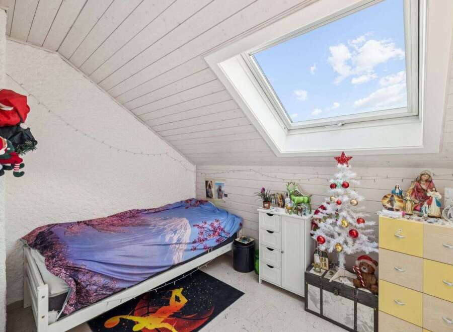 This charming bedroom offers a cozy retreat with its unique sloped ceiling and inviting ambiance.