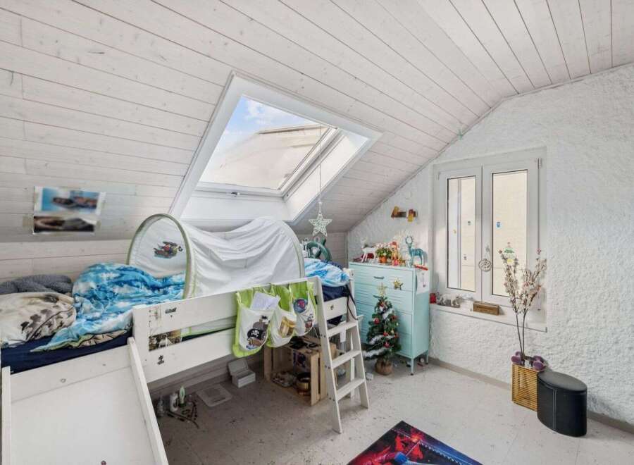 This charming attic bedroom features a cozy bed with a slide, perfect for a child's playful space.