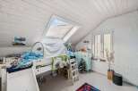 This charming attic bedroom features a cozy bed with a slide, perfect for a child's playful space.