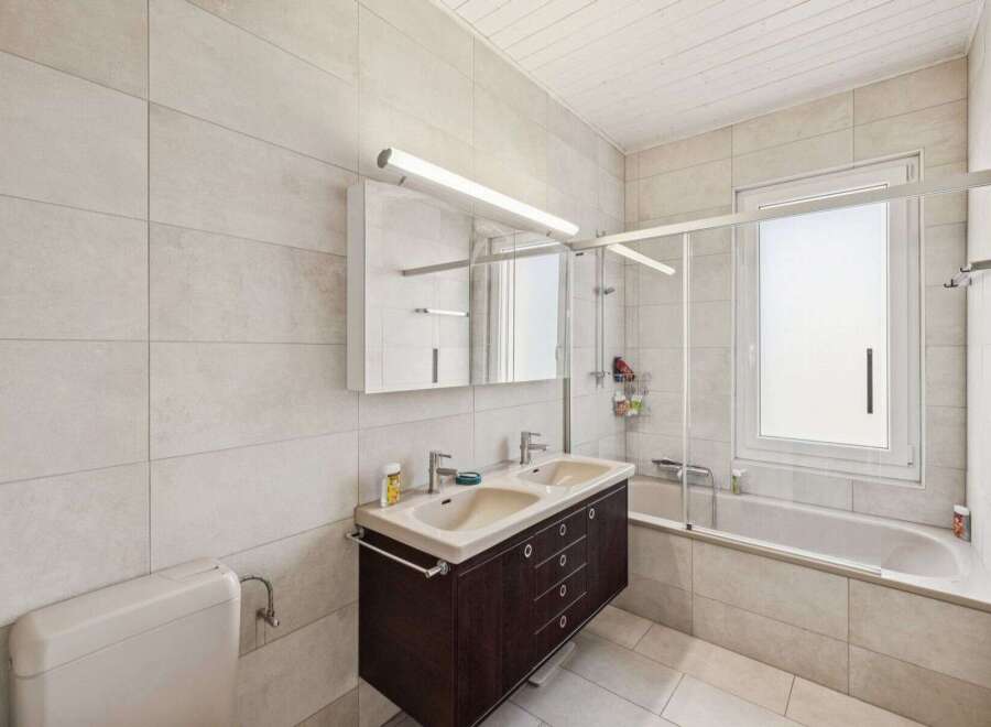 This modern bathroom features a sleek design with a double sink vanity and a bathtub.