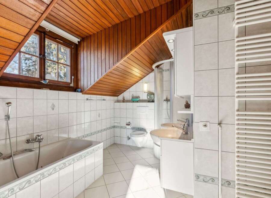 This charming bathroom features a unique sloped wooden ceiling, adding character and warmth to the space.
