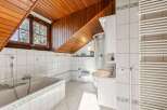 This charming bathroom features a unique sloped wooden ceiling, adding character and warmth to the space.
