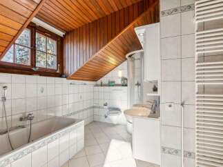 This charming bathroom features a unique sloped wooden ceiling, adding character and warmth to the space.