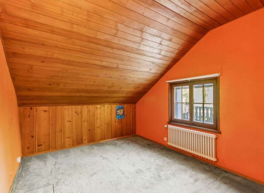 Discover the charm of this unique attic space, featuring a warm wooden ceiling and walls that create a cozy atmosphere.