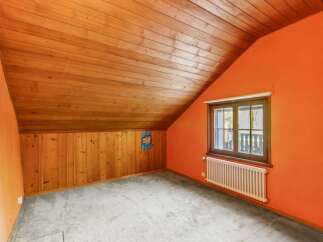 Discover the charm of this unique attic space, featuring a warm wooden ceiling and walls that create a cozy atmosphere.