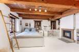 This charming bedroom boasts a rustic aesthetic with exposed wooden beams and a cozy fireplace.