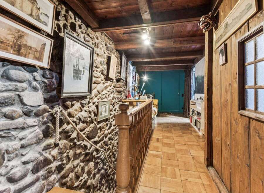 Step into a unique property with this stunning hallway, featuring a rustic stone wall and wooden accents.