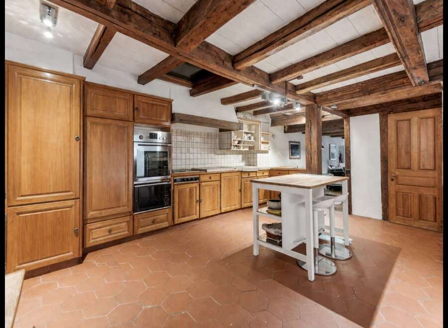Experience rustic charm in this spacious kitchen featuring exposed wooden beams and a warm, inviting atmosphere.