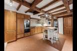 Experience rustic charm in this spacious kitchen featuring exposed wooden beams and a warm, inviting atmosphere.