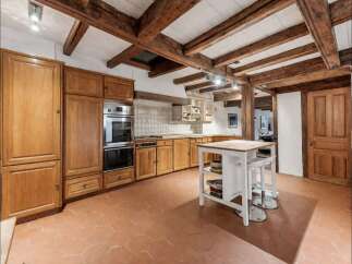 Experience rustic charm in this spacious kitchen featuring exposed wooden beams and a warm, inviting atmosphere.