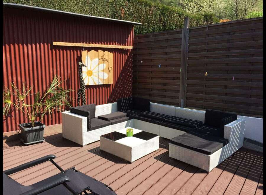 Enjoy outdoor living at its finest with this stunning property! This space features a modern white wicker sofa set with black cushions, perfect for relaxing and entertaining.