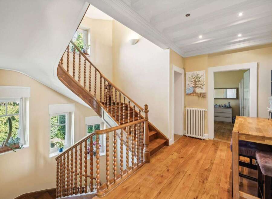 This stunning property boasts a grand staircase with intricate wooden detailing, creating a warm and inviting atmosphere.