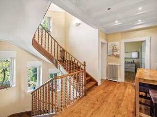 This stunning property boasts a grand staircase with intricate wooden detailing, creating a warm and inviting atmosphere.