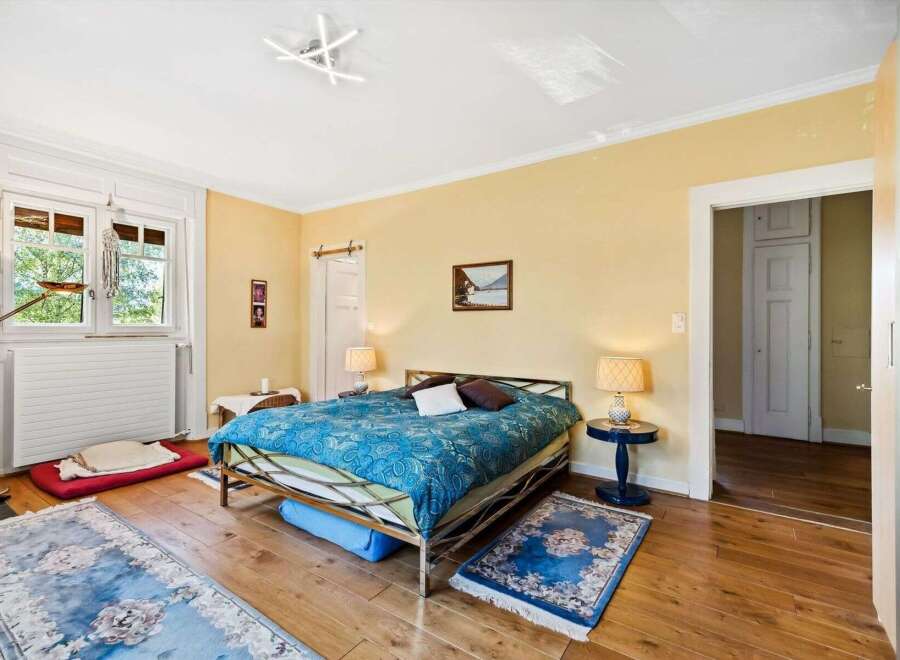 This charming bedroom boasts a serene ambiance with its warm, inviting color palette and natural light streaming through the large window.