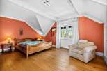 This charming bedroom features a cozy wooden bed frame and warm, inviting hardwood floors.