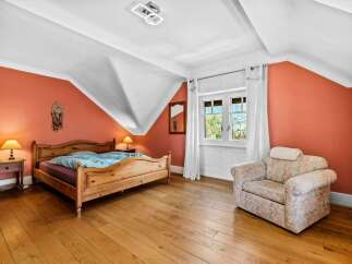 This charming bedroom features a cozy wooden bed frame and warm, inviting hardwood floors.
