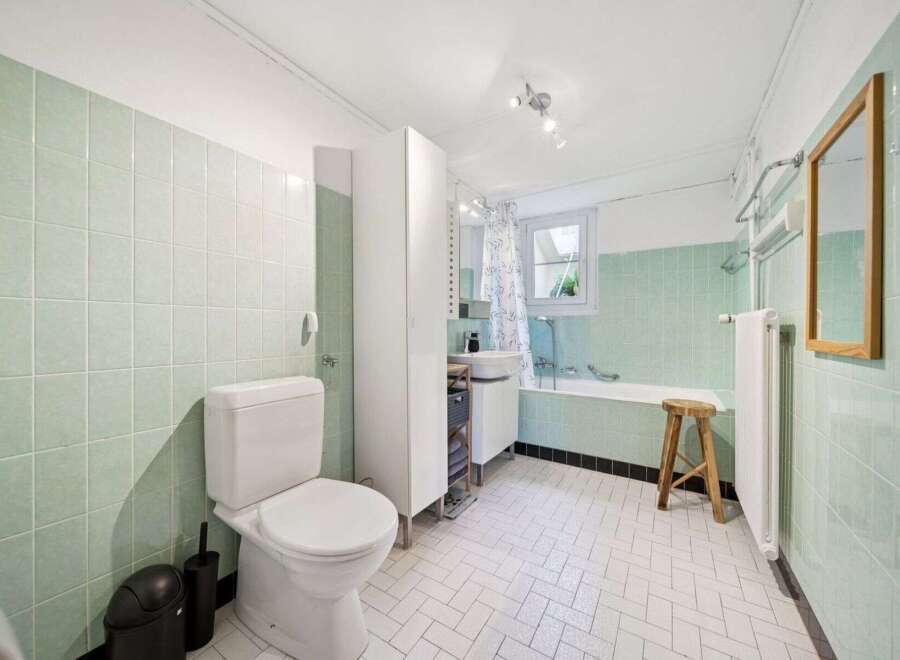 Step into this charming bathroom, featuring a classic design with mint green tiles and a bright, airy feel.