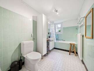 Step into this charming bathroom, featuring a classic design with mint green tiles and a bright, airy feel.