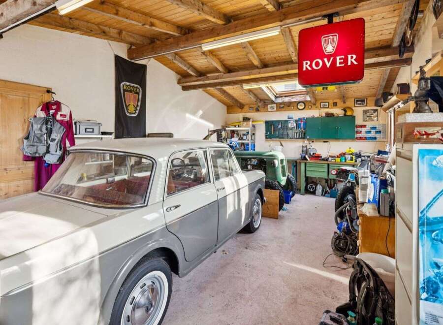 Step into a classic car enthusiast's dream garage! This space features a vintage Rover sign, a beautifully restored classic car, and a well-organized workshop area.