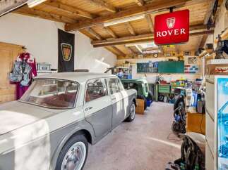 Step into a classic car enthusiast's dream garage! This space features a vintage Rover sign, a beautifully restored classic car, and a well-organized workshop area.