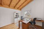 This stunning home office features a beautiful wooden ceiling and a large window that provides ample natural light.