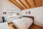 This charming bedroom features a cozy bed with a patterned quilt, complemented by a warm wooden ceiling.