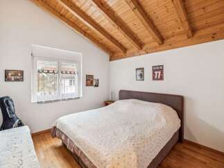 This charming bedroom features a cozy bed with a patterned quilt, complemented by a warm wooden ceiling.