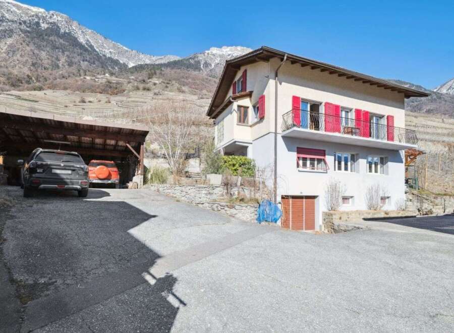 Nestled in a picturesque mountain setting, this charming property boasts a beautiful facade with vibrant red shutters.