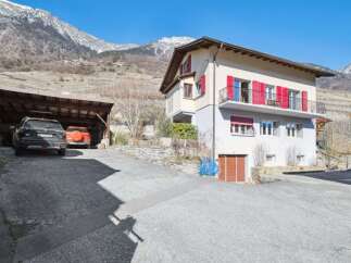 Nestled in a picturesque mountain setting, this charming property boasts a beautiful facade with vibrant red shutters.