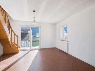 Discover this bright and airy living space, featuring a beautiful wooden staircase and a charming pendant light.