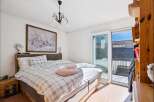 This bright and airy bedroom offers a serene retreat with its neutral color palette and ample natural light.