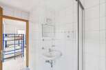 This property features a clean and modern bathroom with white tiled walls and a sleek sink.