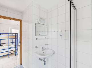 This property features a clean and modern bathroom with white tiled walls and a sleek sink.