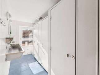 This well-maintained restroom features clean white walls and a bright blue tiled floor, creating a fresh and inviting atmosphere.