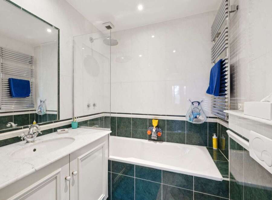 This stunning bathroom boasts a modern design with sleek white tiles and a contrasting dark green border.