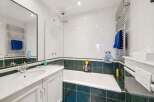 This stunning bathroom boasts a modern design with sleek white tiles and a contrasting dark green border.