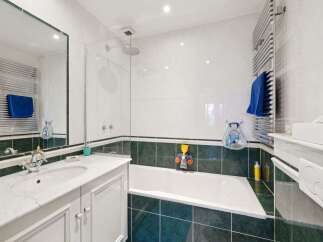 This stunning bathroom boasts a modern design with sleek white tiles and a contrasting dark green border.